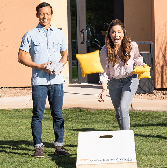 Man and woman playing a bag toss game at WaterWalk Atlanta