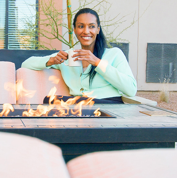 Woman holding a coffee cup next to the fire pit at WaterWalk Boise - Meridian