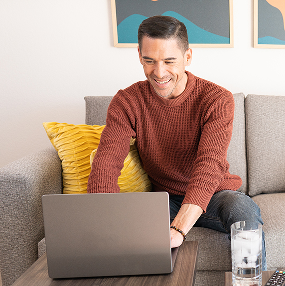 Man working on laptop at WaterWalk apartment.